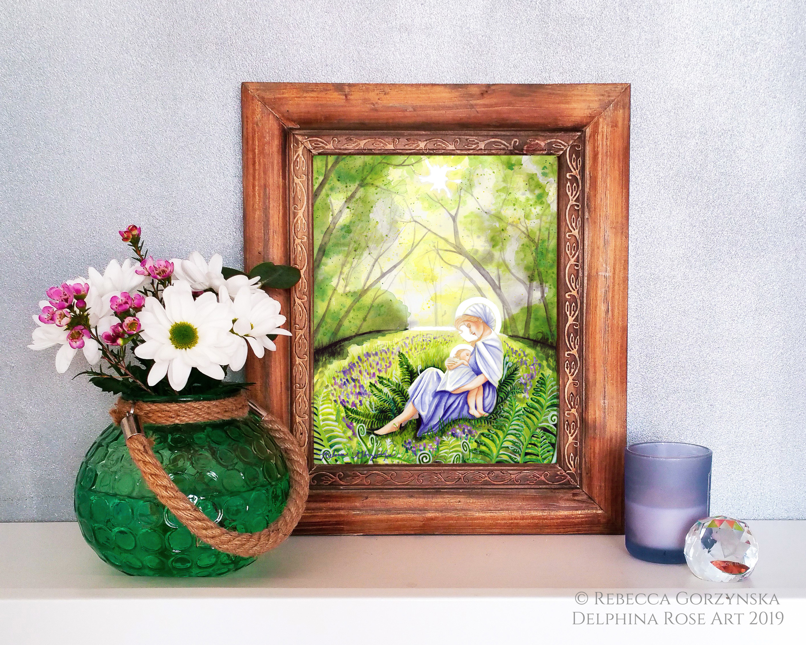 mother in blue dress nursing baby in green forest