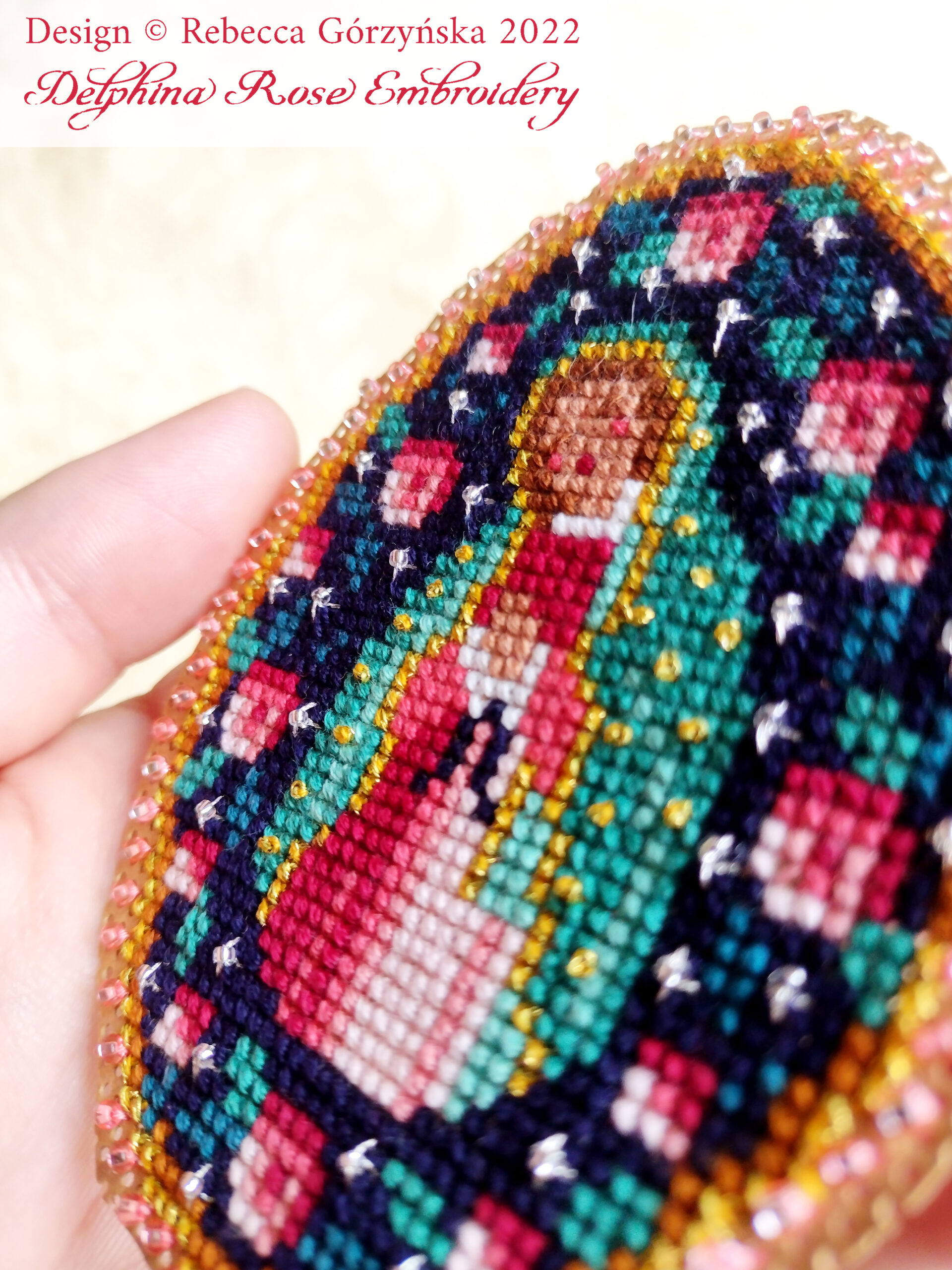 hand holding cut out finished cross stitch project on perforated paper of Our Lady of Guadalupe